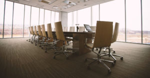large conference room in a skyscraper with glass windowed walls and a empty conference table with a dozen chairs around it