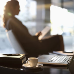 image of a lawyer sitting in a chair in front of large window by her desk while reading a stack of papers